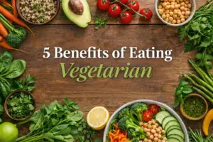 Flat lay of fresh vegetarian foods with text “5 benefits of eating vegetarian” on a wooden background